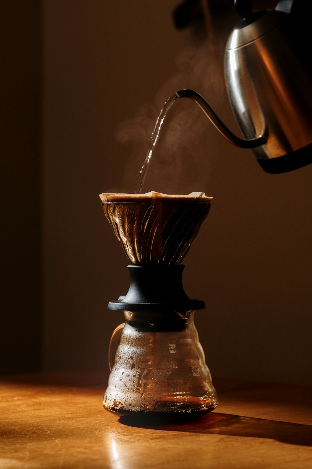 Barista pouring a slow steady stream from a gooseneck kettle over a Kalita Wave dripper